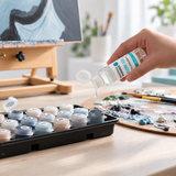 Eine Hand gibt einen Tropfen Flow Aid in einen offenen Acrylfarbtopf.